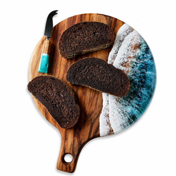 Handcrafted natural wooden chopping board with handle used for cutting meat, cheese and bread in a modern kitchen.