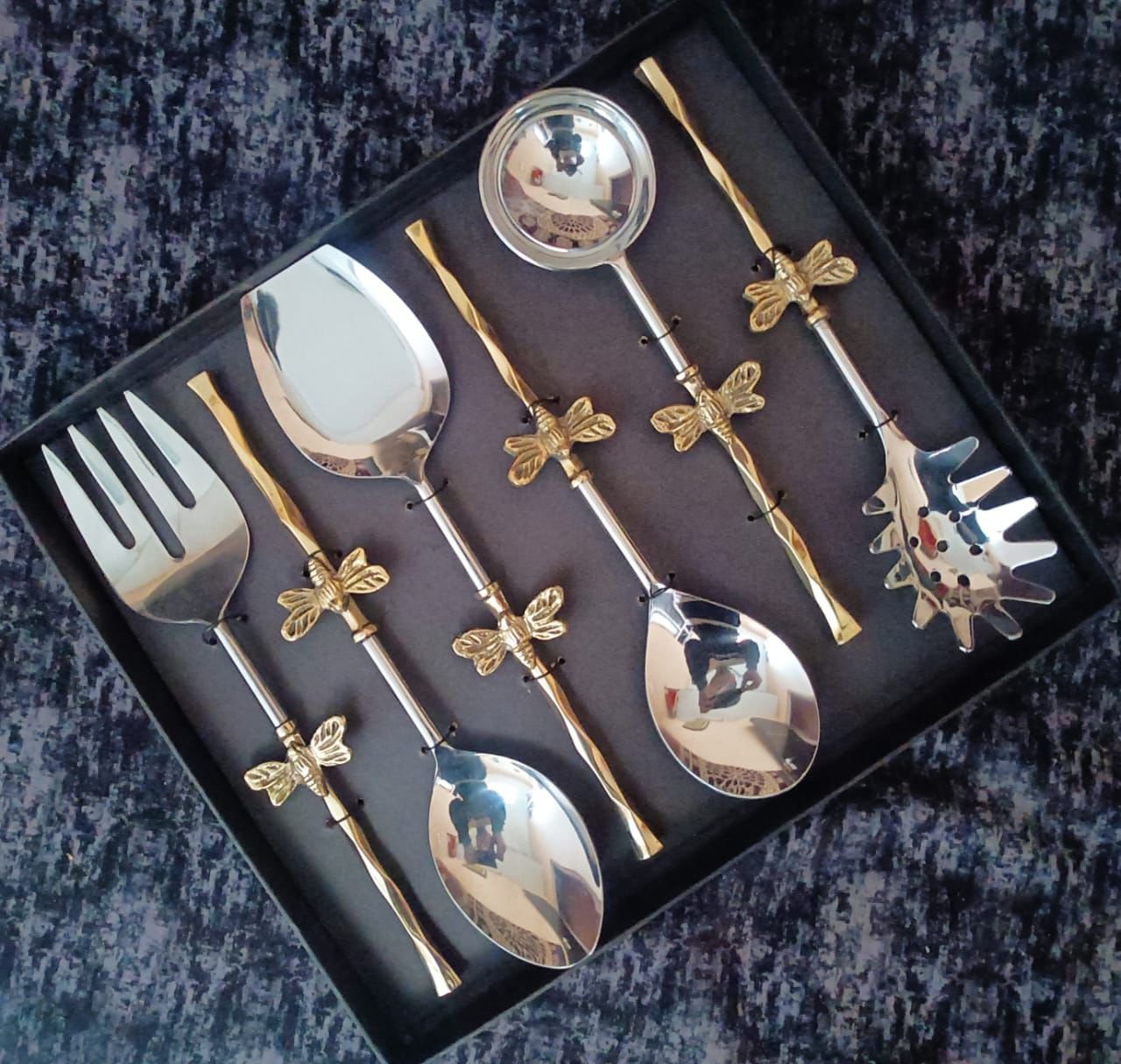 steel-brass-serving-utensils-table.webp Steel and brass serving utensils arranged on luxury dining table