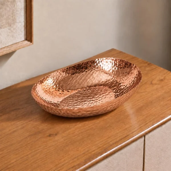 Hammered copper decorative oval bowl on luxury tabletop
