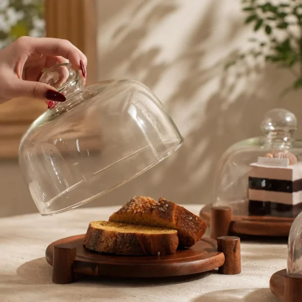 Wooden cake stand with glass dome cover displaying bread